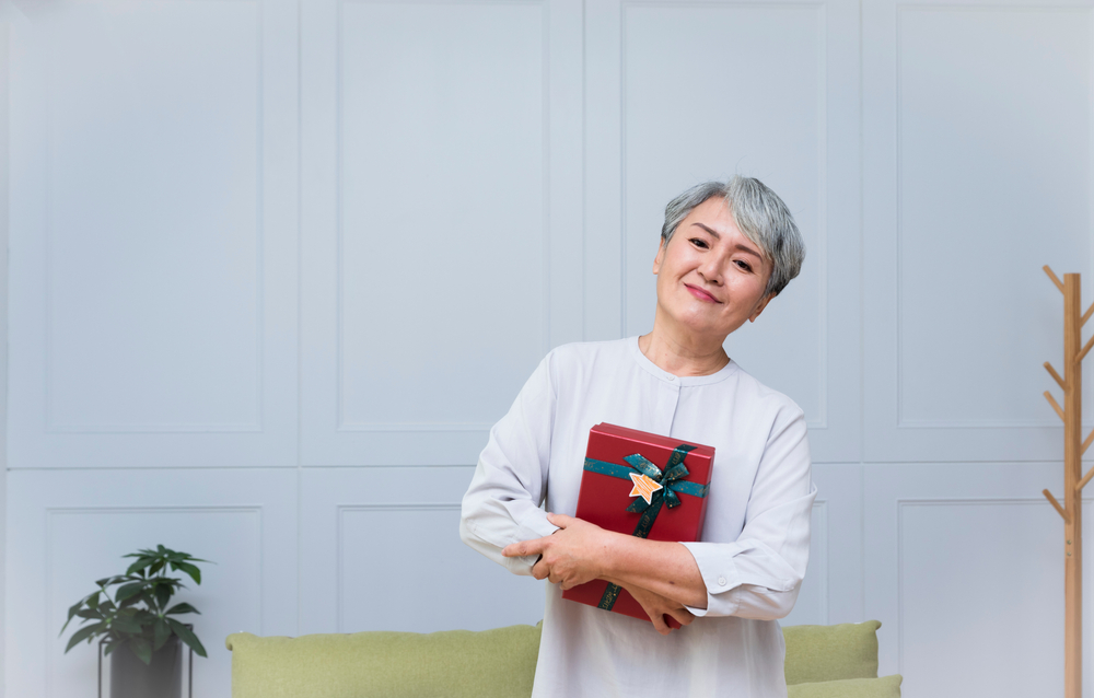 Senior woman is holding a gift with a smile