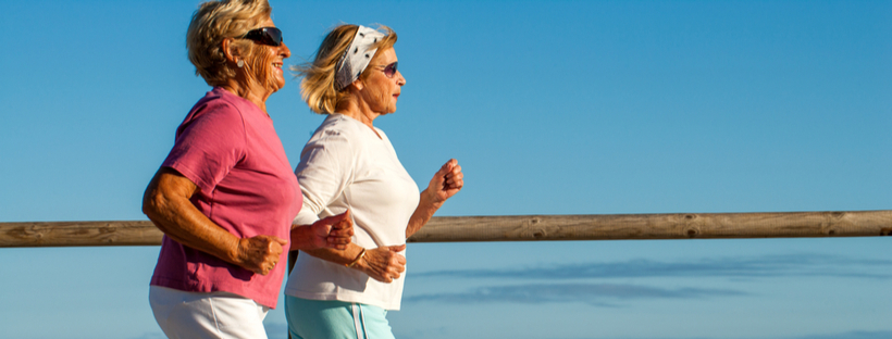 Two senior women jogging together outdoors