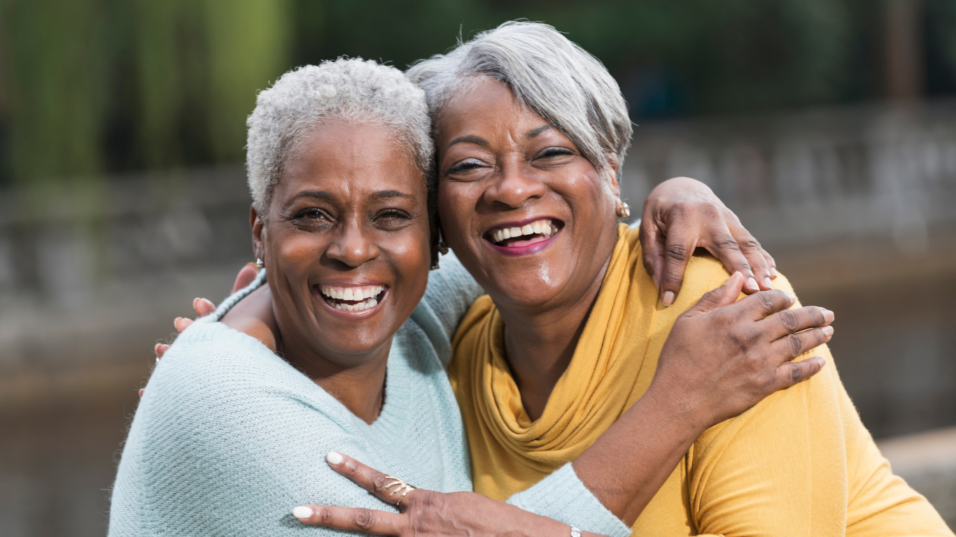 Two senior women smiling while embracing