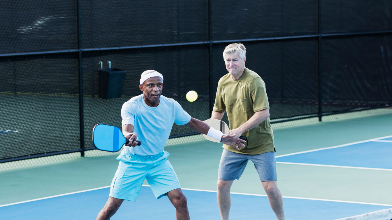 Two senior friends playing pickleball together