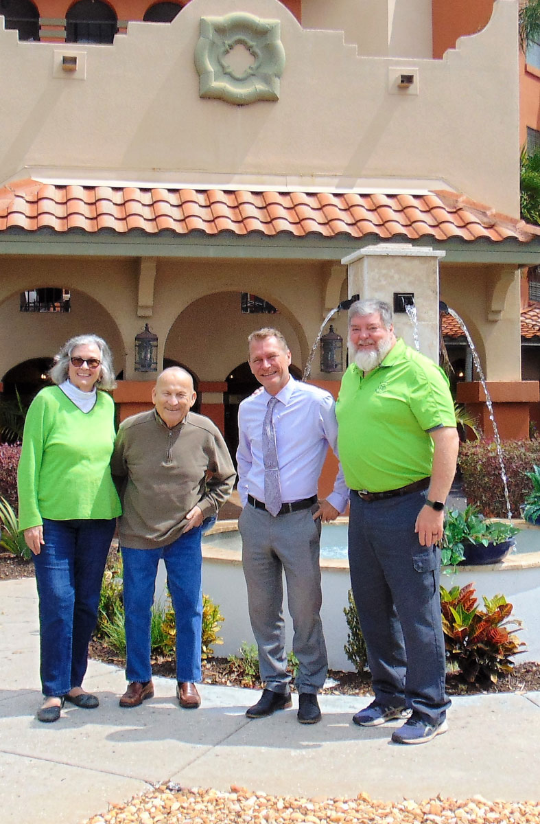 Staff members pose for a picture with residents in front of Lake Seminole Square senior living community.