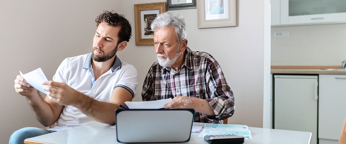 Senior man going through paperwork with his son