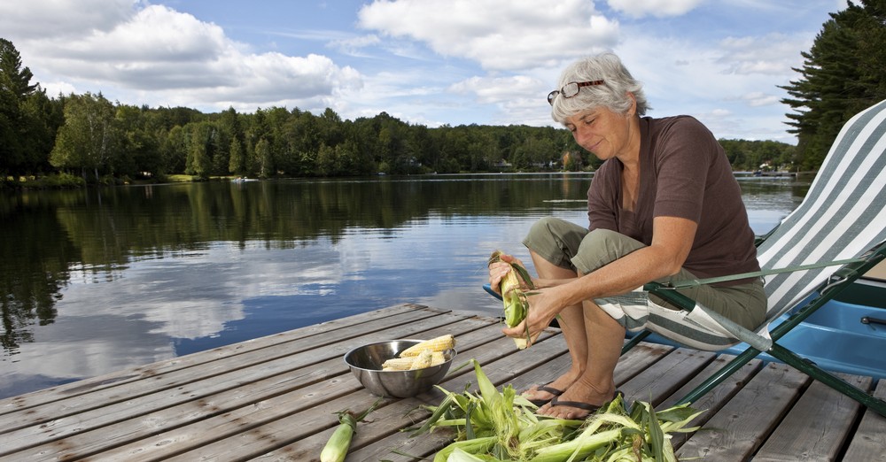 Senior woman shucking corn by a lake