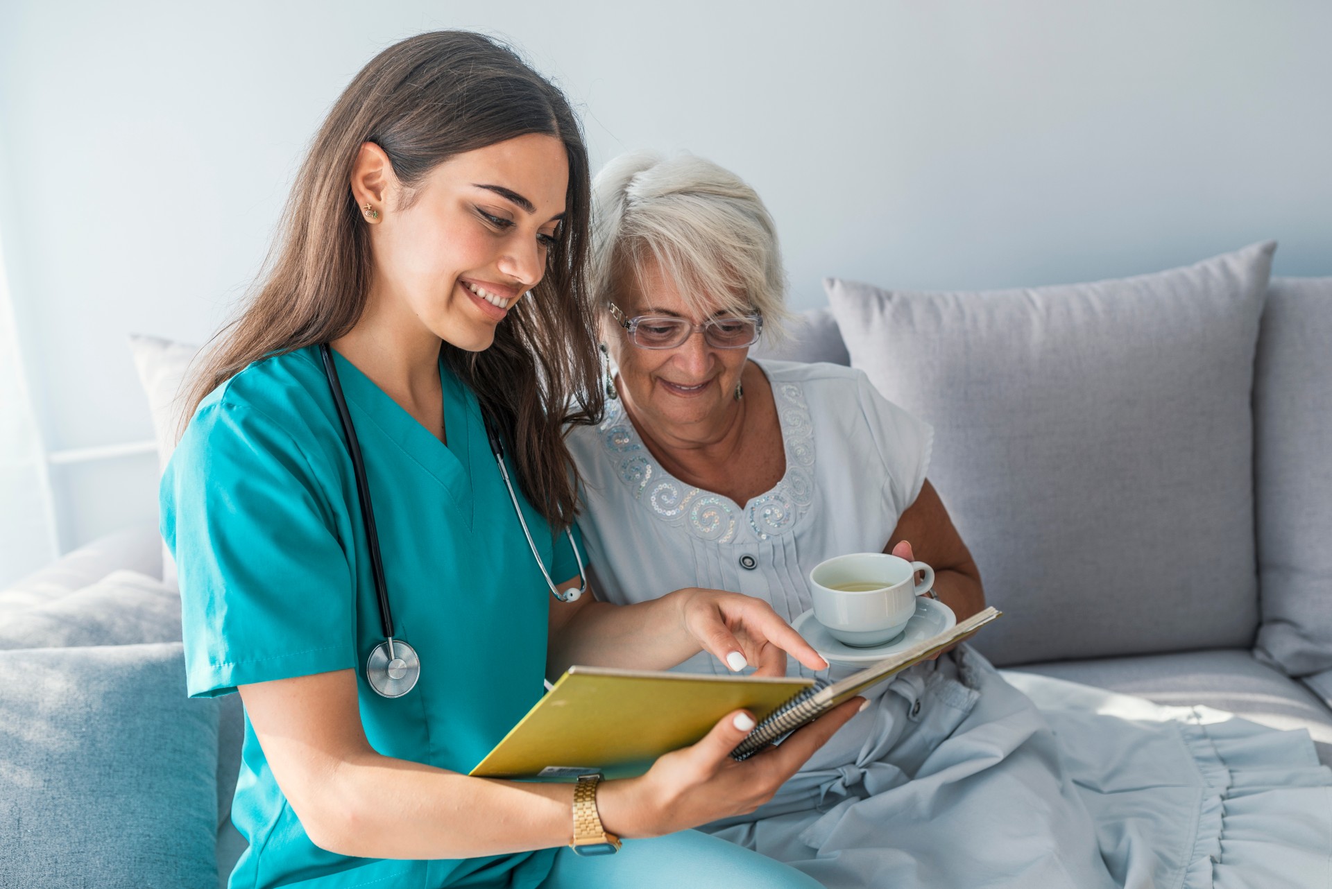 Happy senior woman and her caregiver reading a book